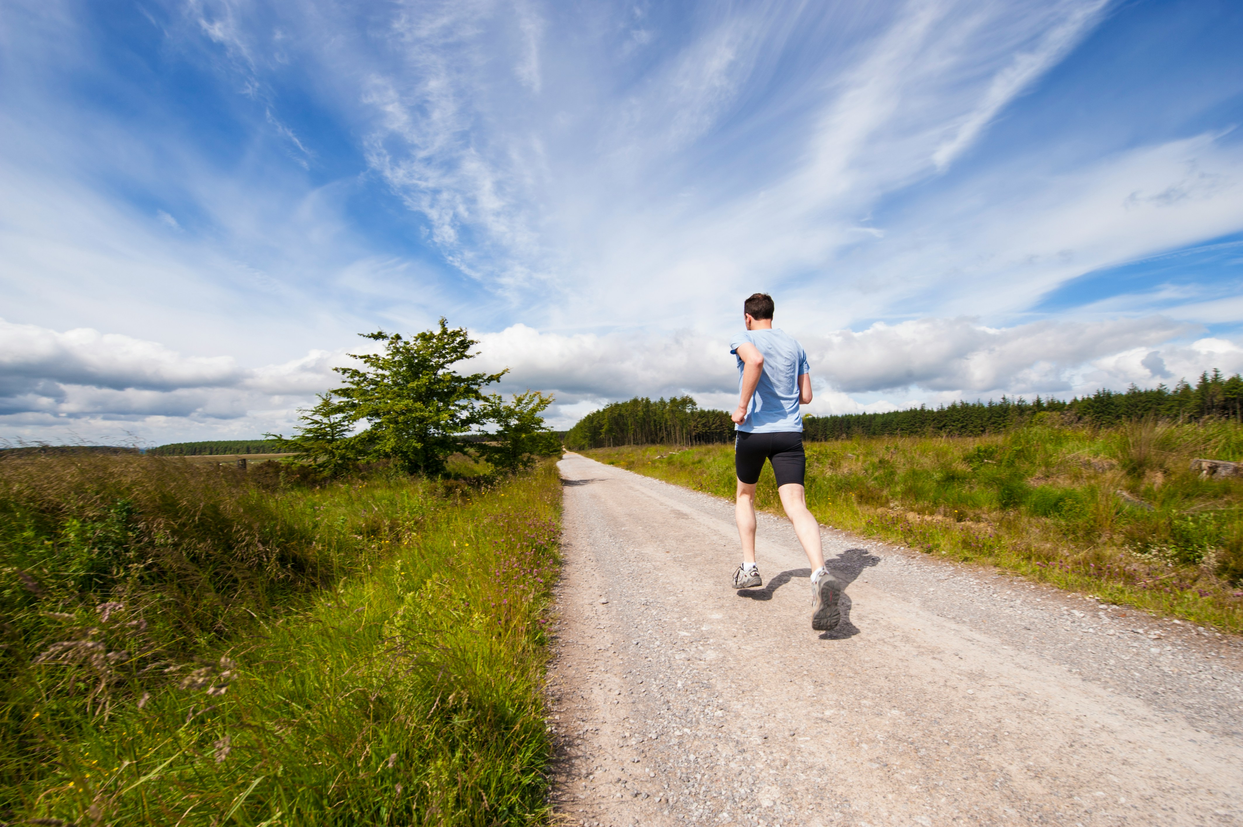 man running in blue shirt on dirt road