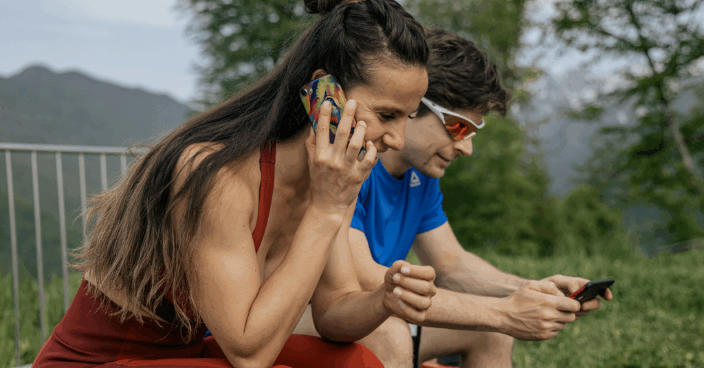 athlete on phone and another athlete checking their training plan 