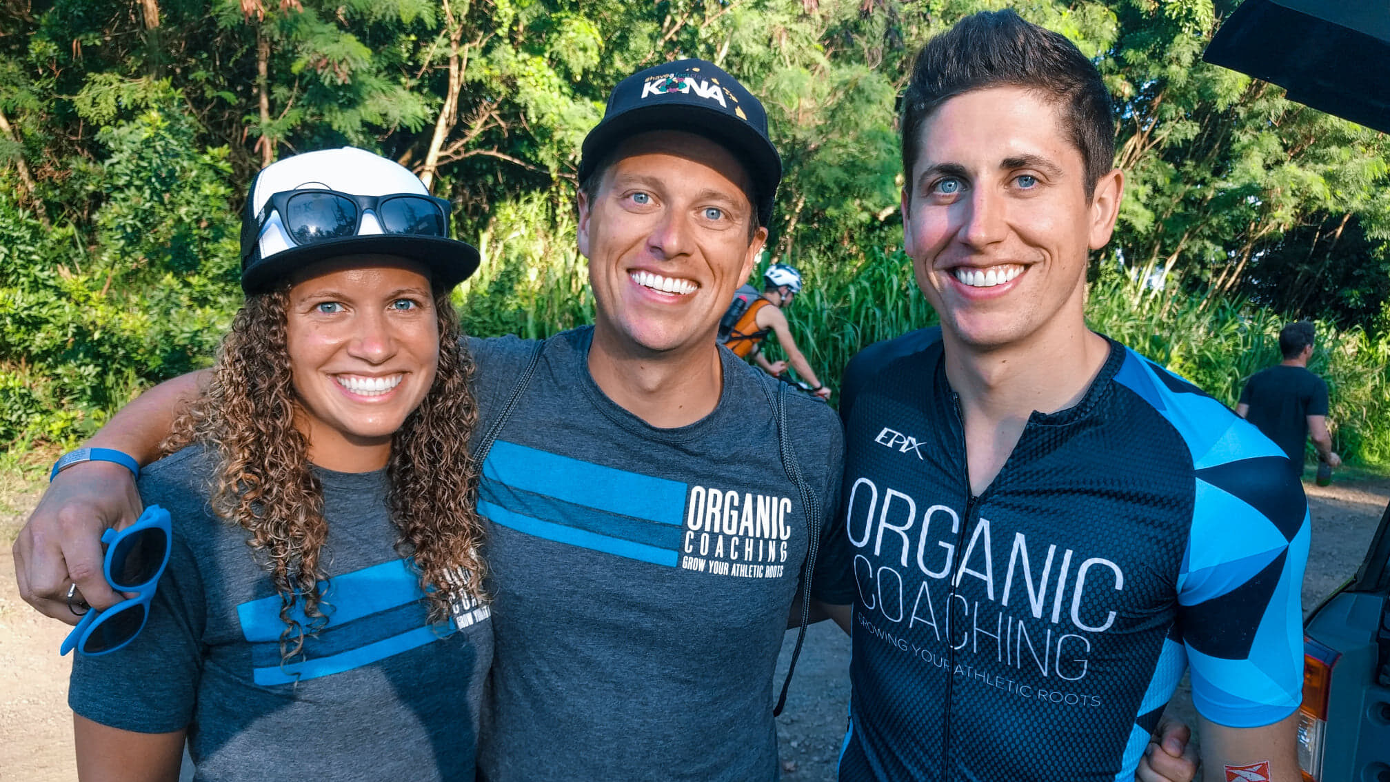 two triathlon coaches and one athlete smiling before a race