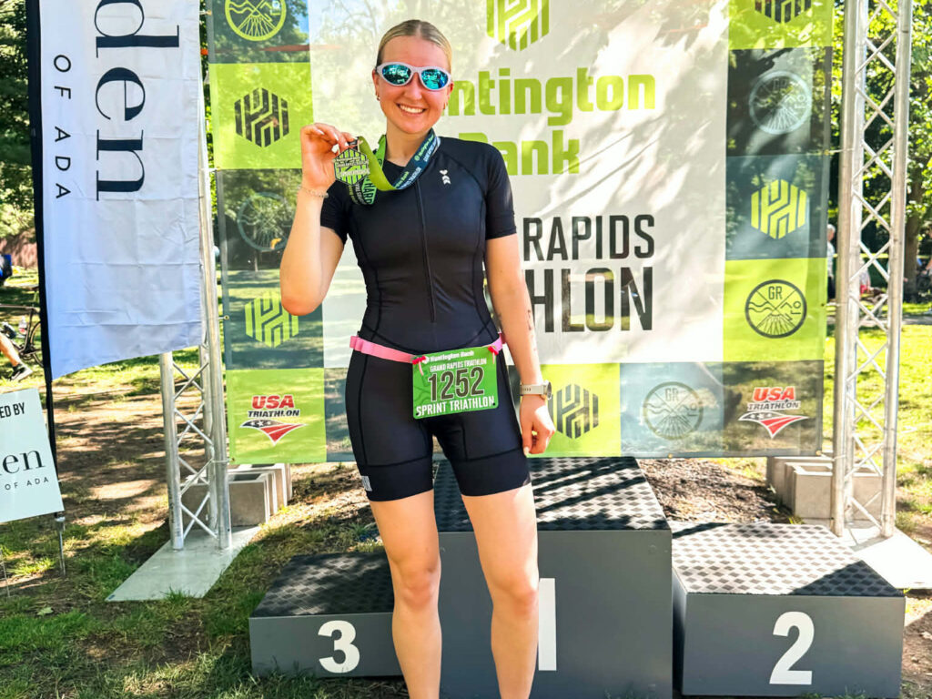 girl smiling holder her medal after triathlon race