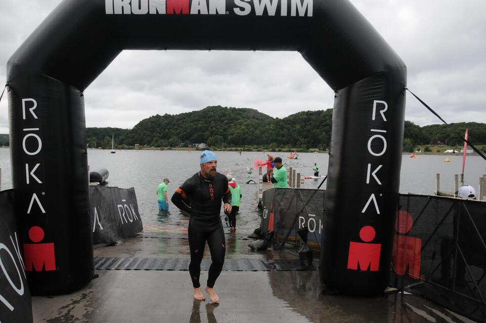 man in roka wetsuit exiting the swim of a 70.3 Ironman race